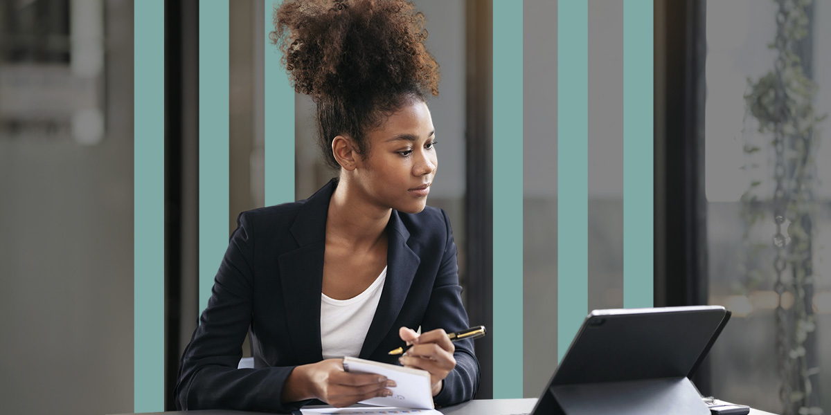 a woman sits at a desk with a tablet and a pen